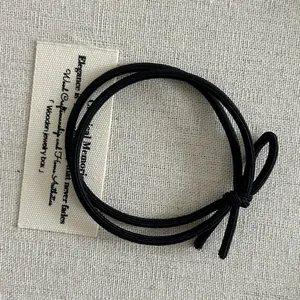 Macro shot of double-strand elastic black hair tie featuring a classic knotted bow tie design