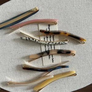 Ensemble élégant de barrettes en acétate coloré avec base dorée sur tissu blanc