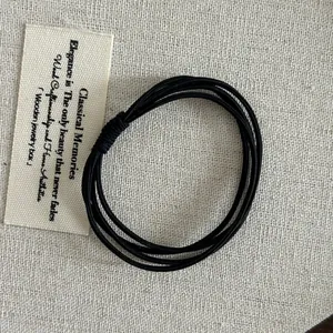 Macro shot of durable multi-strand black elastic hair bands on beige fabric background