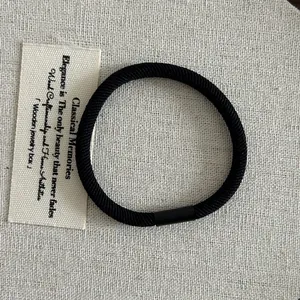 Detailed macro view of black elastic hair tie with spiral texture and matte fastener
