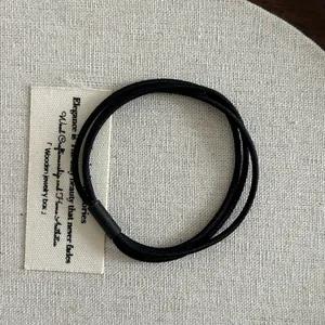 Detail of high-elastic black multi-strand hair tie with matte finish connector on linen