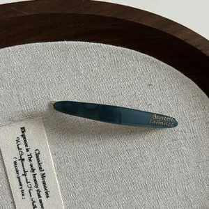 Détail d'une barrette à cheveux en acétate bleu canard avec lettrage doré élégant