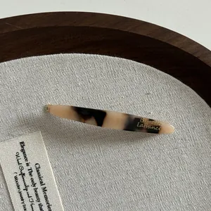 Détail d'une barrette en acétate écaille de tortue avec inscription dorée sur fond lin