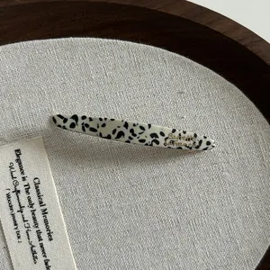 Détail de la barrette élégante en acétate noir et blanc avec texte doré Barrette La France
