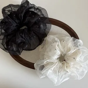 Détail de chouchous élégants en organza à pois en couleurs noir classique et blanc crème