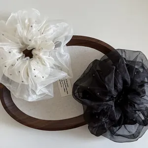 Détail de chouchous élégants en organza à pois et noir uni posés sur un plateau chic