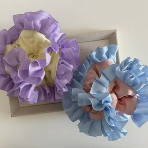 Dettaglio di scrunchies bicolore in tessuto a coste dai toni pastello su vassoio