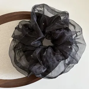 Texture détaillée du chouchou en organza noir à pois sur fond de bois rustique