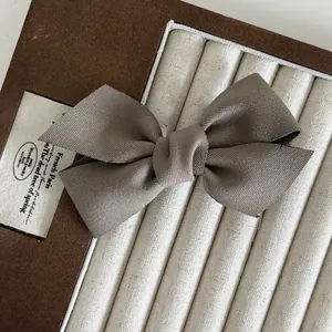 Elegante fermaglio per capelli a fiocco in raso marrone scuro su portagioie in velluto