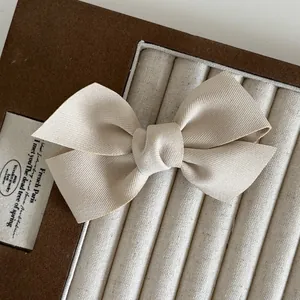 Elegante fermaglio per capelli a fiocco in raso beige su un espositore per gioielli in velluto