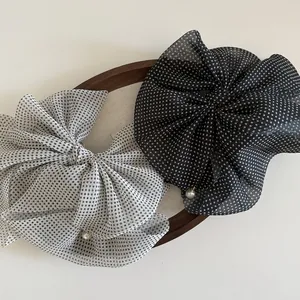 Detail of polka dot tulle bow hair clips with elegant faux pearl pendants on wood