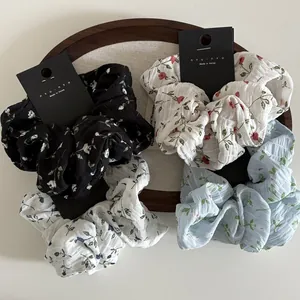 Close-up of four floral print fabric hair scrunchies on a wooden display tray
