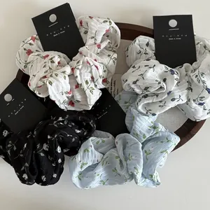 Close-up of floral print scrunchies in chiffon fabric displayed on a wooden tray