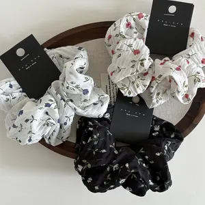 Detailed texture of floral scrunchie set in white, blue, and black on a wooden tray
