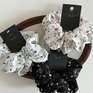 Detailed macro view of three floral fabric scrunchies in red, blue, and black patterns