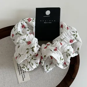 Detail of floral scrunchie with red flowers on white fabric and brand display card