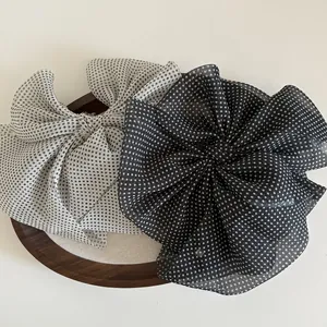 Elegant polka dot mesh bow hair clips in black and white on a wooden tray