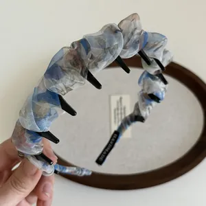 Détail d'un serre-tête en mousseline fleurie bleue avec dents et étiquette faite main