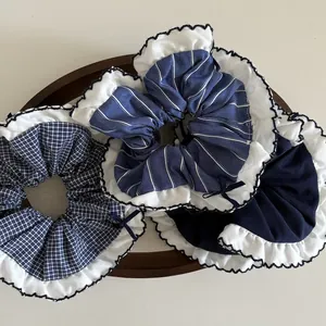 Close-up of navy blue plaid and striped scrunchies with white lace edges on wood tray
