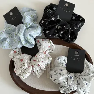 Set of four floral print scrunchies in diverse colors displayed on a wooden tray