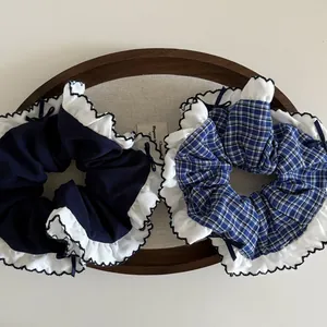 Detail of navy blue and plaid scrunchies set with white ruffle edges and bows