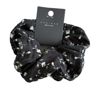 Floral print black scrunchie with white flowers and pleated cotton fabric texture