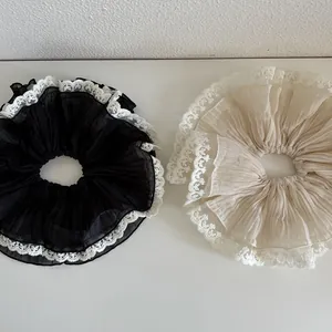 Detail of oversized pleated chiffon scrunchies with intricate white floral lace trim