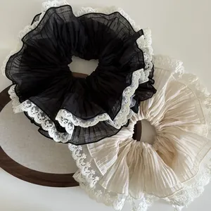 Macro view of oversized pleated scrunchie with lace trim in black and beige tones