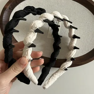 Detail of twisted fabric headbands with anti-slip inner teeth in black and beige