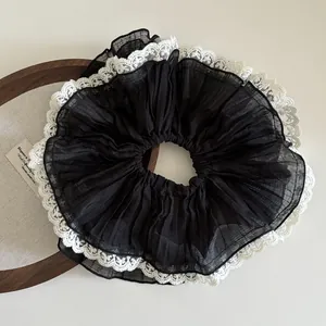 Detail of oversized black pleated chiffon scrunchie with delicate white lace edges