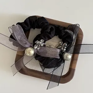 Detail of black scrunchies with sheer organza bows, grey pearls, and flower rhinestones