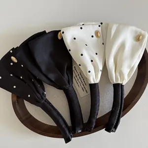 Details von Satin-Bogen-Bananen-Haarspangen in Schwarz und Creme mit Goldakzenten