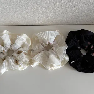 Three-pack floral pleated scrunchies with elegant lace edges in cream and black tones