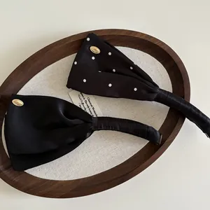 Details von Satin-Haarreifen in Schwarz und gepunktet mit eleganten Metallemblemen