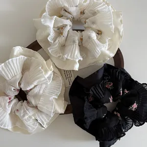 Close-up of floral pleated scrunchies set in chiffon on a wooden plate