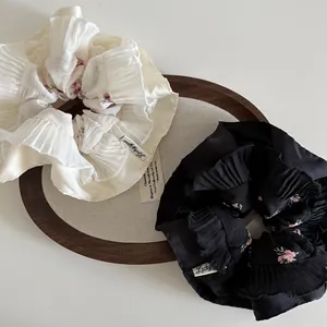 Close-up of pleated floral scrunchies with Lucky Girl labels on a wooden tray