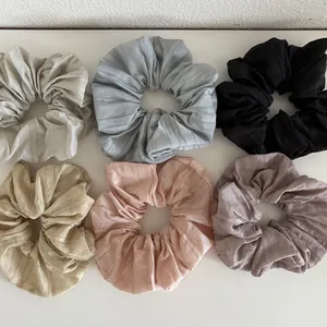 Flat lay of six Morandi color chiffon hair scrunchies with fine pleated fabric textures