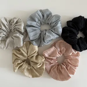 Detail of five assorted scrunchies showing ribbed fabric texture and neutral pastel colors