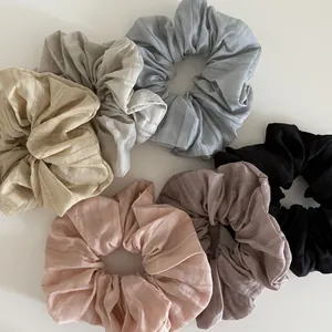 Close-up of six pleated fabric scrunchies in pastel colors with striped texture