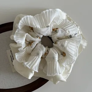 Detail of cream floral scrunchie with pleated mesh lace on dark wood background