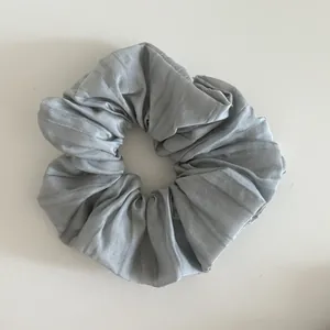 Detail of silver gray pleated hair scrunchie with vertical striped fabric texture