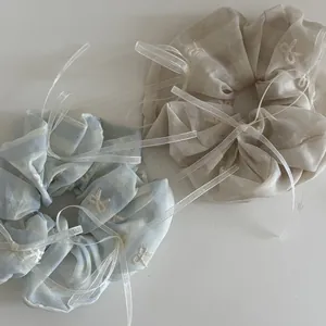 Détail de chouchous bleu clair et beige avec broderie nœud blanc et rubans soyeux