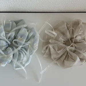 Détail de chouchous en tulle rayé bleu clair et beige avec broderie papillon blanc
