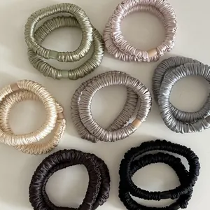 Close-up of premium satin scrunchies with pleated texture and resin buckles in various colors