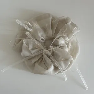 Détail du chouchou beige avec broderie de nœuds et ruban transparent en maille douce