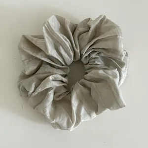 Detail of cream pleated fabric scrunchie with soft vertical texture and elegant design