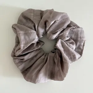 Detailed view of dusty pink silk scrunchie featuring elegant pleated fabric texture