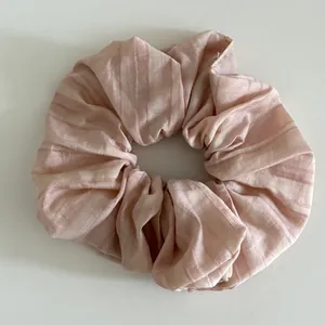 Detail of light pink striped fabric hair scrunchie with pleated texture and soft finish