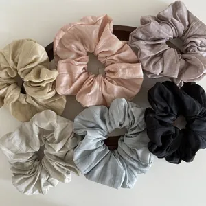 Set of six colorful pleated fabric scrunchies in pastel tones on a wooden tray
