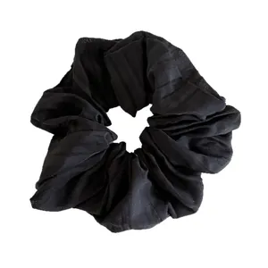 Elegant large black pleated hair scrunchie with subtle vertical stripe texture on white background